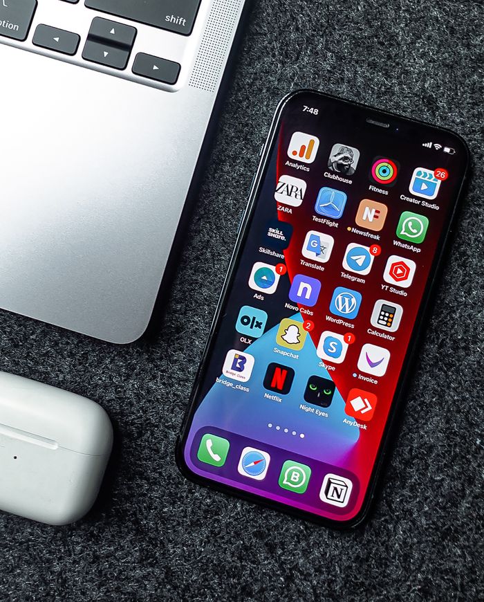 who-we-are Flat lay of a smartphone, laptop, and earphones on a grey surface. Perfect for tech and gadget themes.